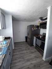 Kitchen with dark countertops, appliances with stainless steel finishes, and wood finished floors