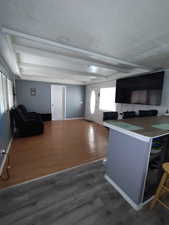 Kitchen featuring beam ceiling, baseboards, open floor plan, and wood finished floors