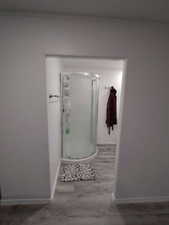 Bathroom with a shower stall, baseboards, and wood finished floors