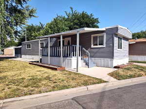 Manufactured / mobile home with covered porch and a front lawn