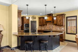 Kitchen with built in microwave, a sink, stainless steel oven, custom exhaust hood, and decorative backsplash