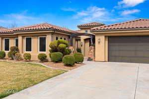 Mediterranean / spanish home with a tile roof, stucco siding, concrete driveway, a garage, and a front lawn