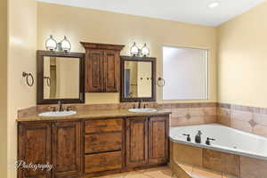 Full bath featuring double vanity, tile patterned flooring, a sink, and a bath