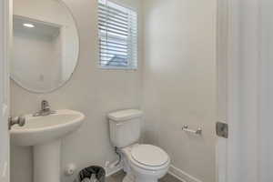 Half bathroom with baseboards, a sink, and toilet