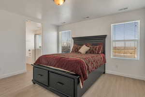 Bedroom with light wood-type flooring, visible vents, and baseboards