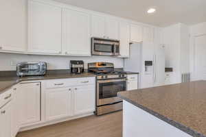 Kitchen with a toaster, stainless steel appliances, visible vents, light wood-style flooring, and white cabinets