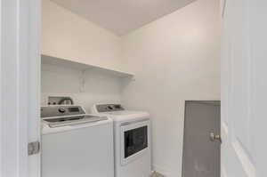 Laundry area with laundry area, baseboards, and washing machine and clothes dryer