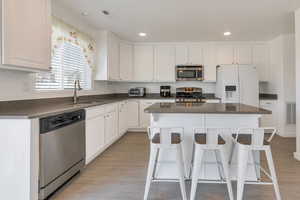 Kitchen featuring appliances with stainless steel finishes, dark countertops, a sink, and visible vents