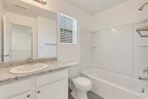 Bathroom featuring visible vents, vanity, toilet, and tub / shower combination