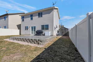 Back of house with a storage shed, a fenced backyard, a patio, and an outbuilding