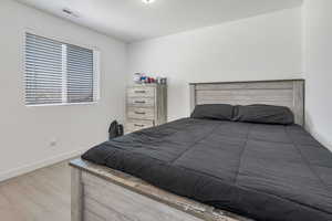 Bedroom featuring visible vents, baseboards, and wood finished floors