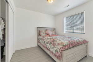 Bedroom featuring baseboards, visible vents, a closet, and wood finished floors