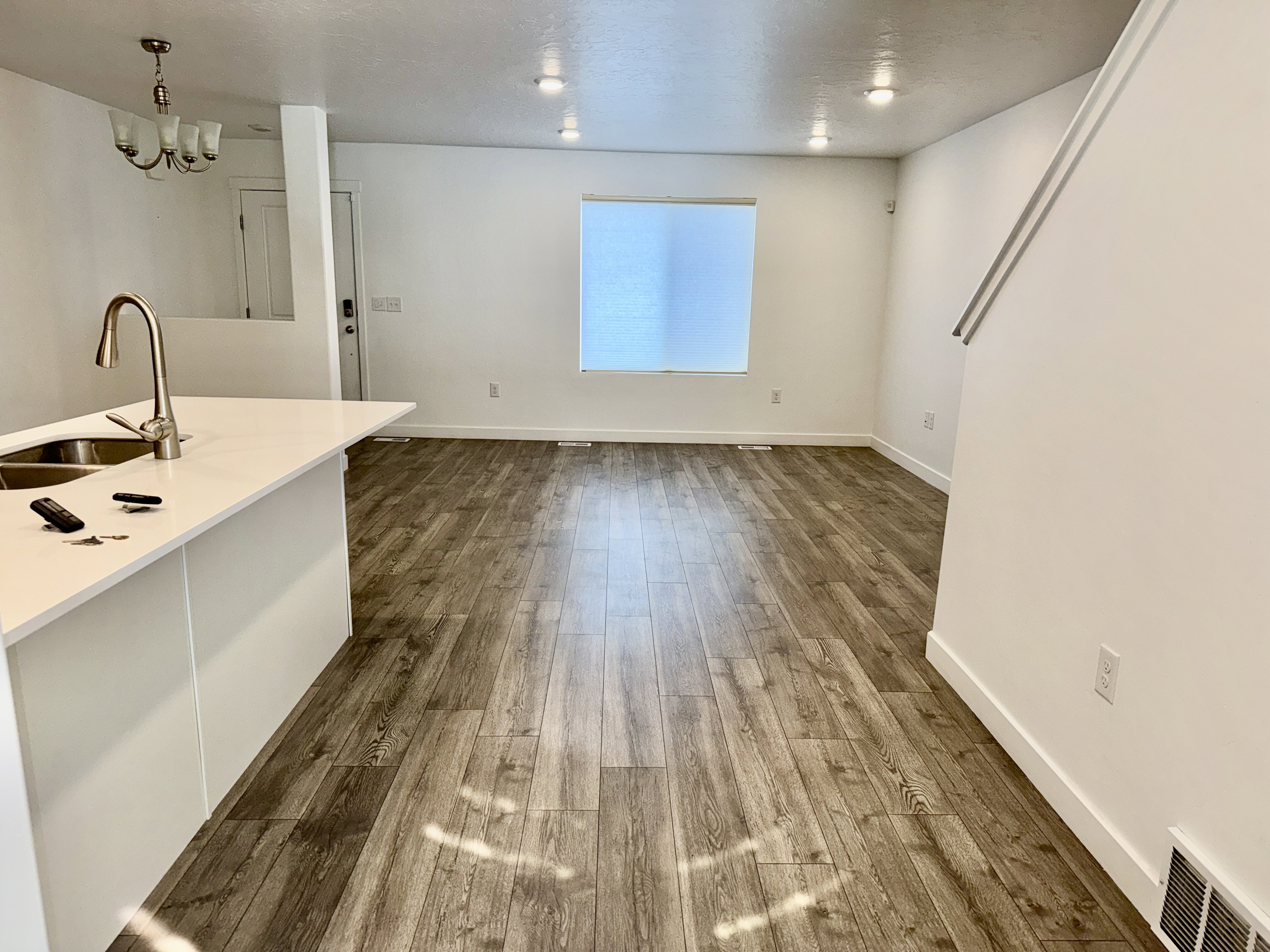 Open-concept living area featuring wood-finish flooring, recessed lighting, and a kitchen island with an undermount sink and gooseneck faucet
