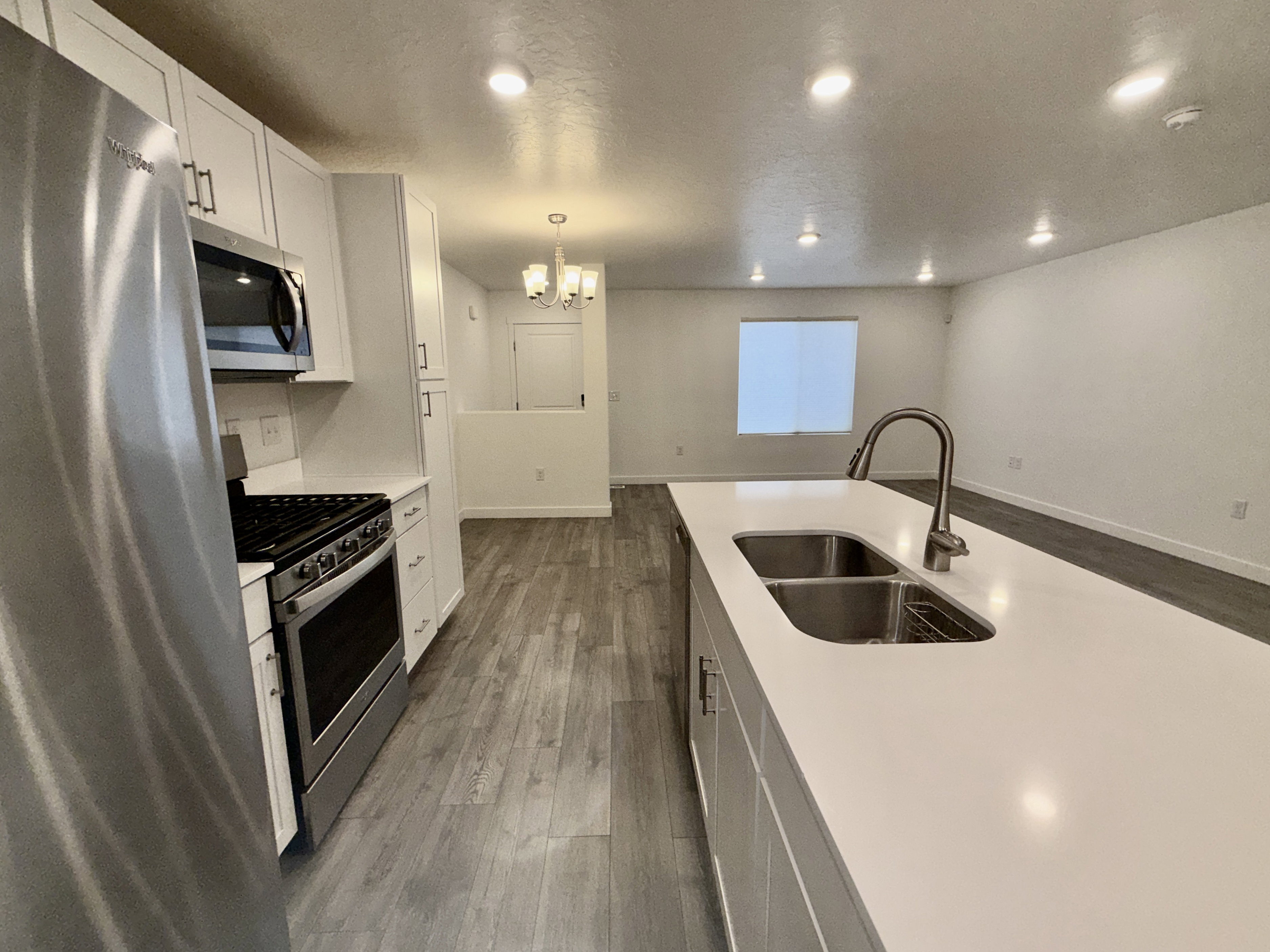 Modern kitchen featuring a large island with an undermount double-basin sink and pull-down faucet
