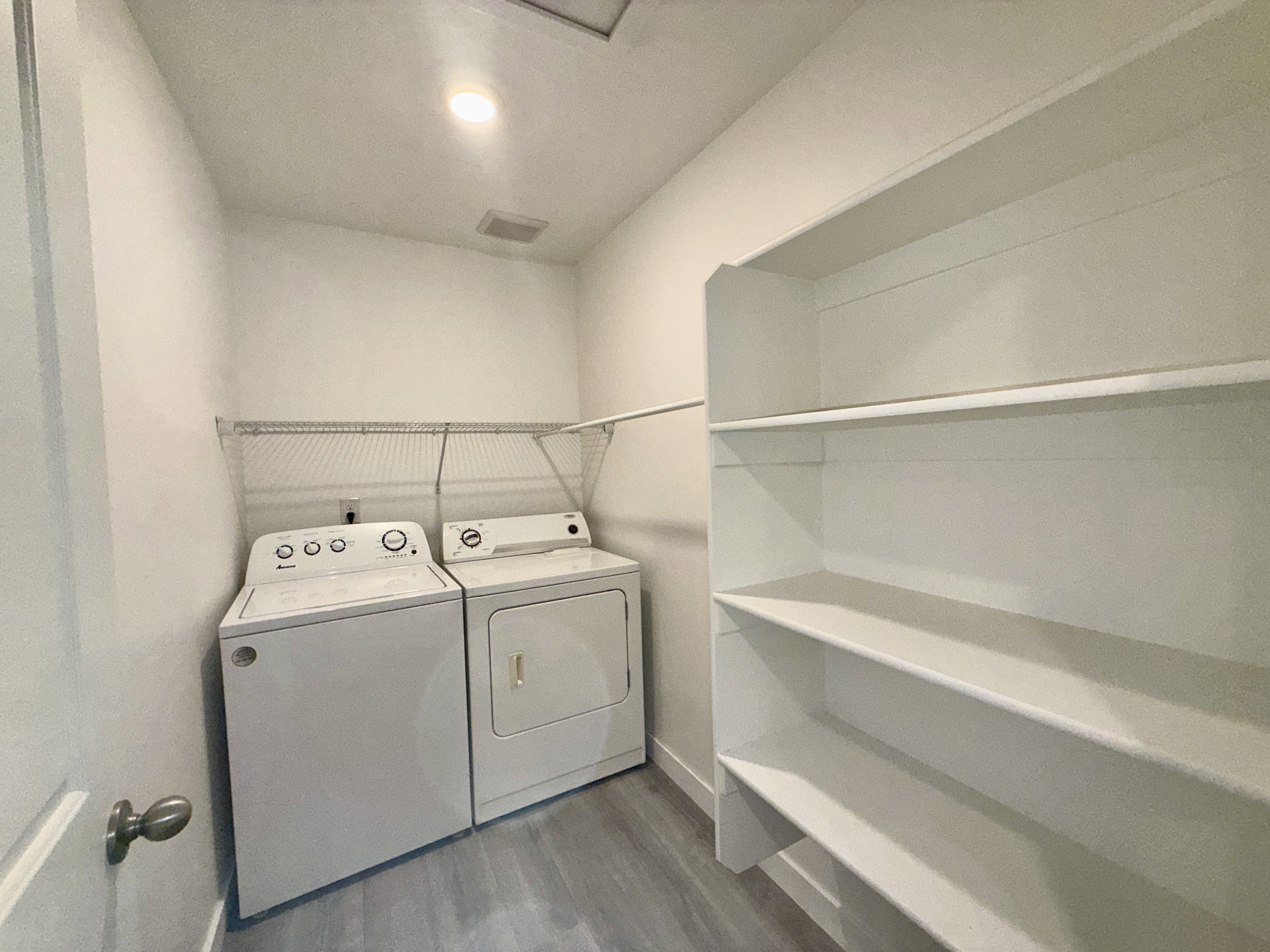 Dedicated laundry area featuring wood-finish flooring and a built-in shelving unit