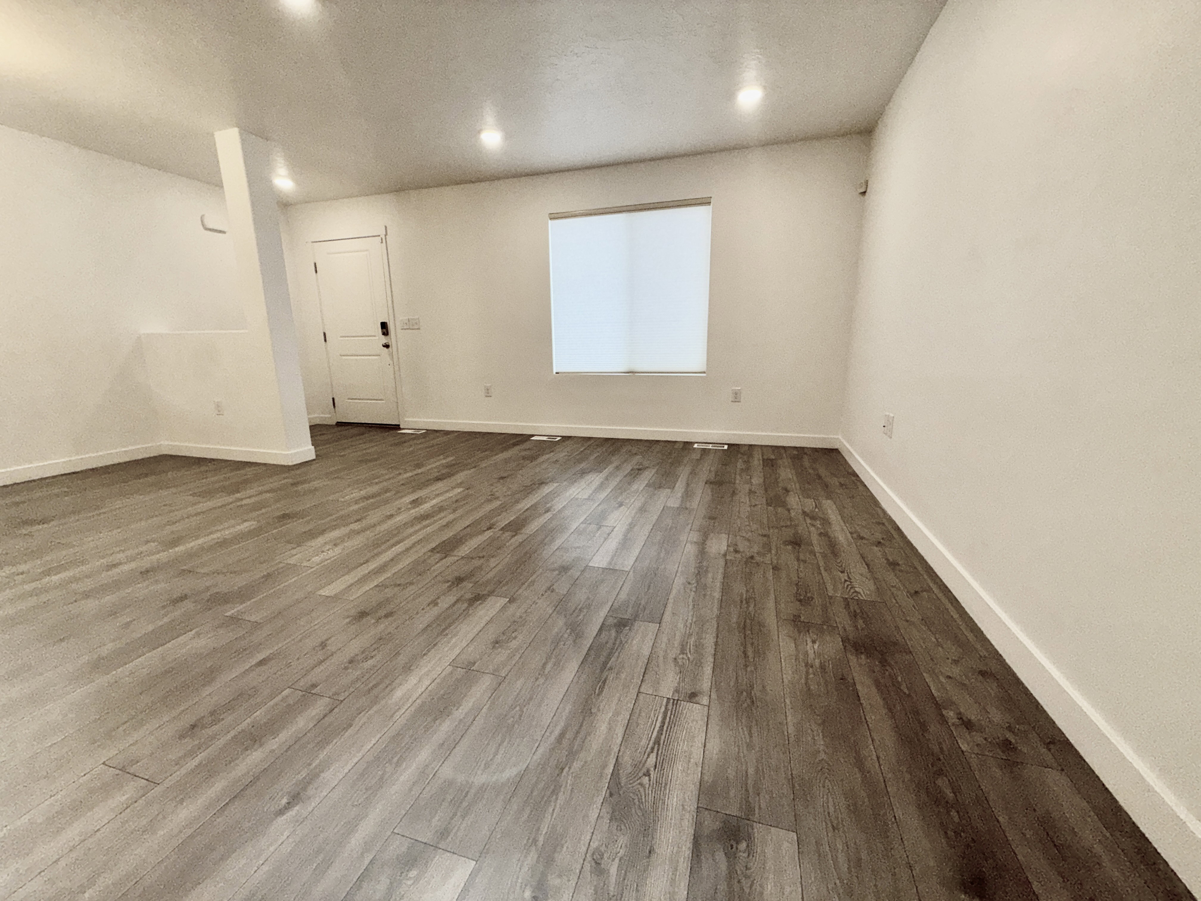 Spacious room featuring wood-finish flooring, recessed lighting, and a neutral color palette