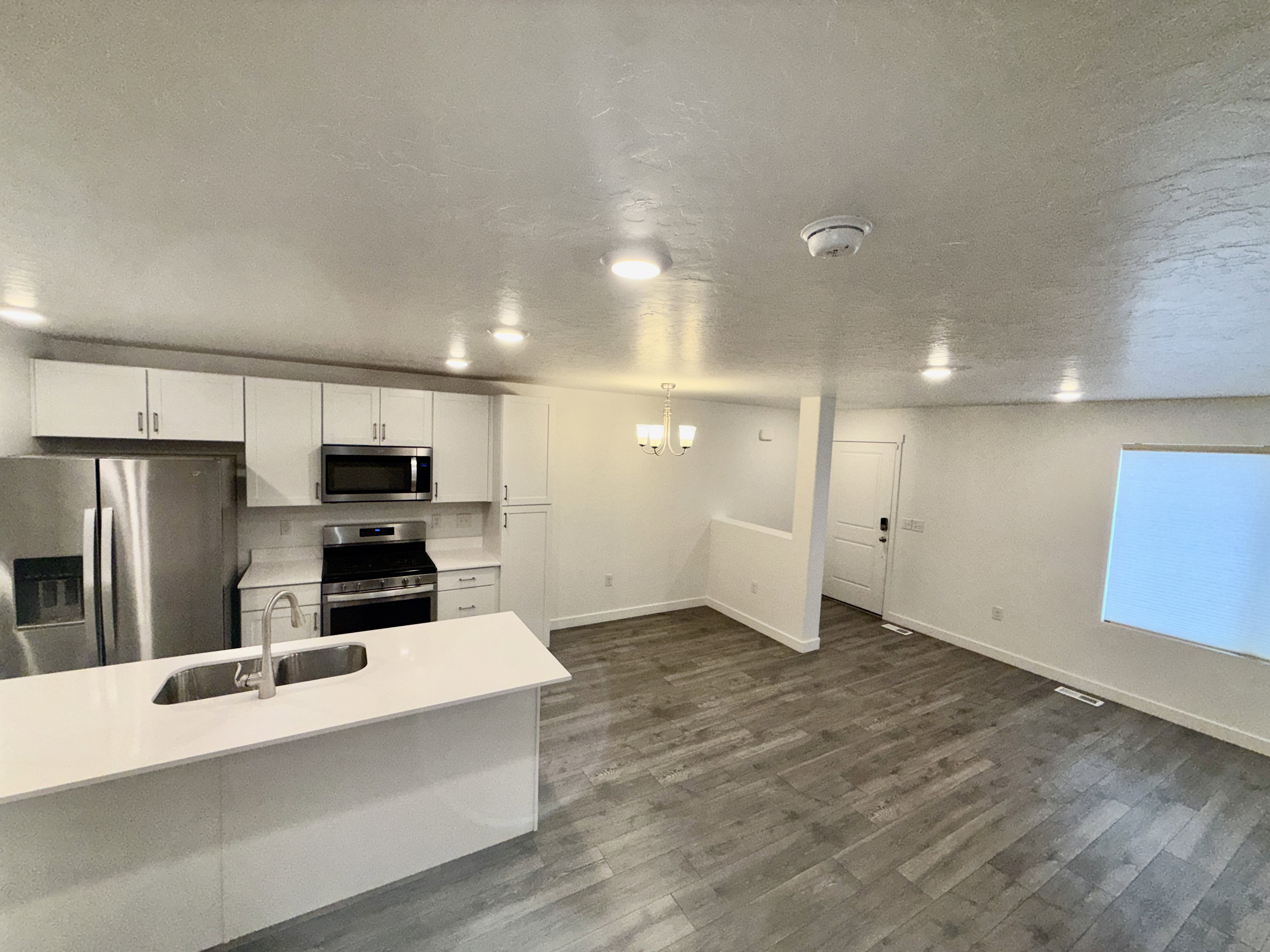Modern kitchen featuring white cabinetry, stainless steel appliances, and a central island with an undermount sink