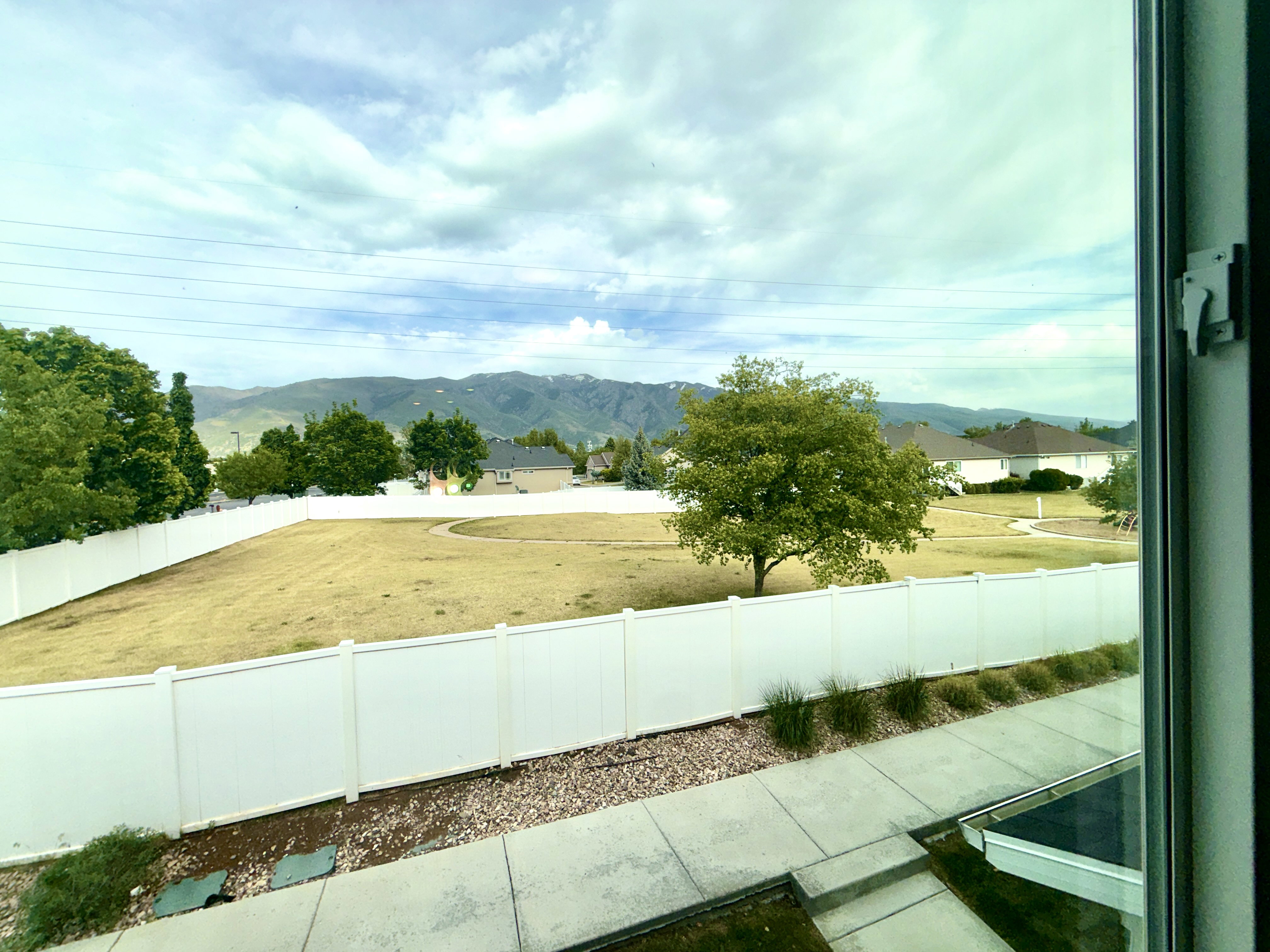 Mountain backdrop from a window overlooking a fenced yard