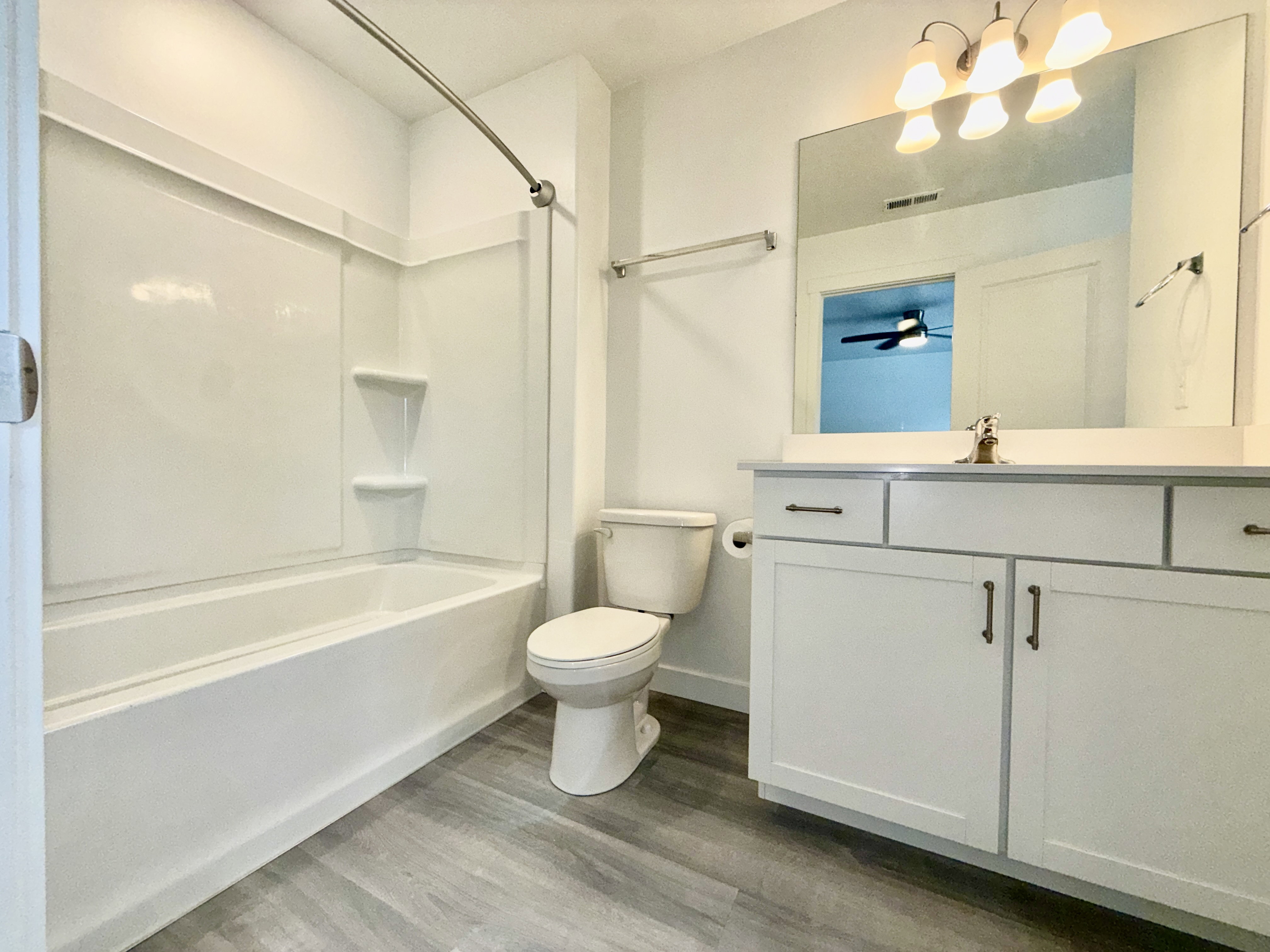 Contemporary bathroom featuring a white vanity with paneled doors, coordinating countertop, and a large wall-mounted mirror