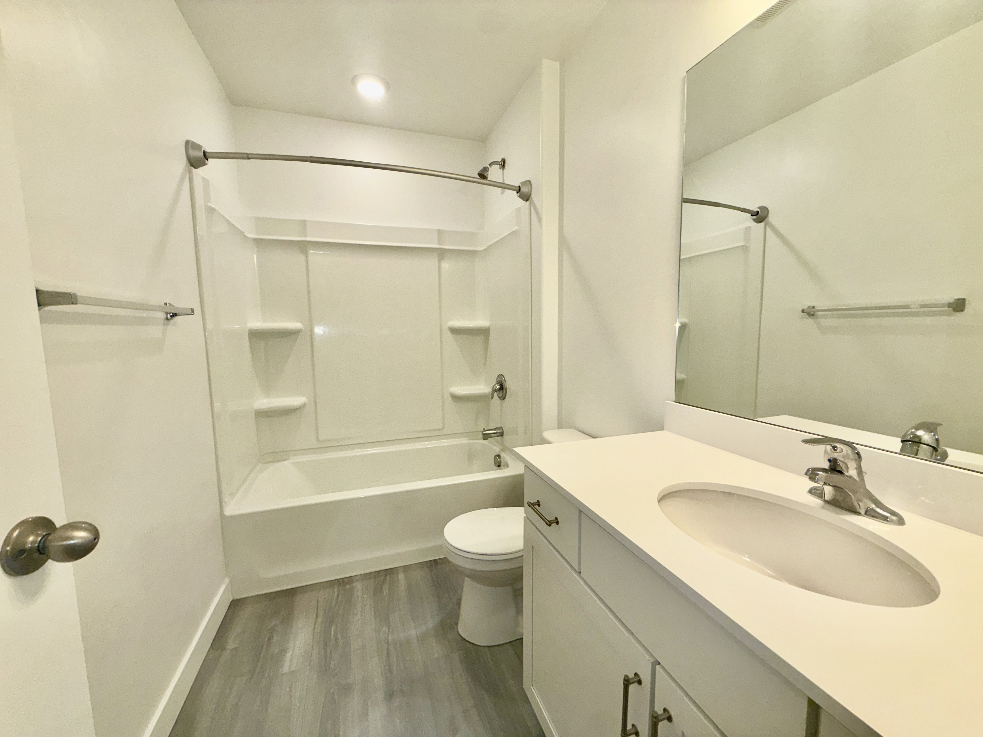 Bathroom featuring a white vanity with an undermount sink, a large wall-mounted mirror, and a white bathtub with an integrated shower