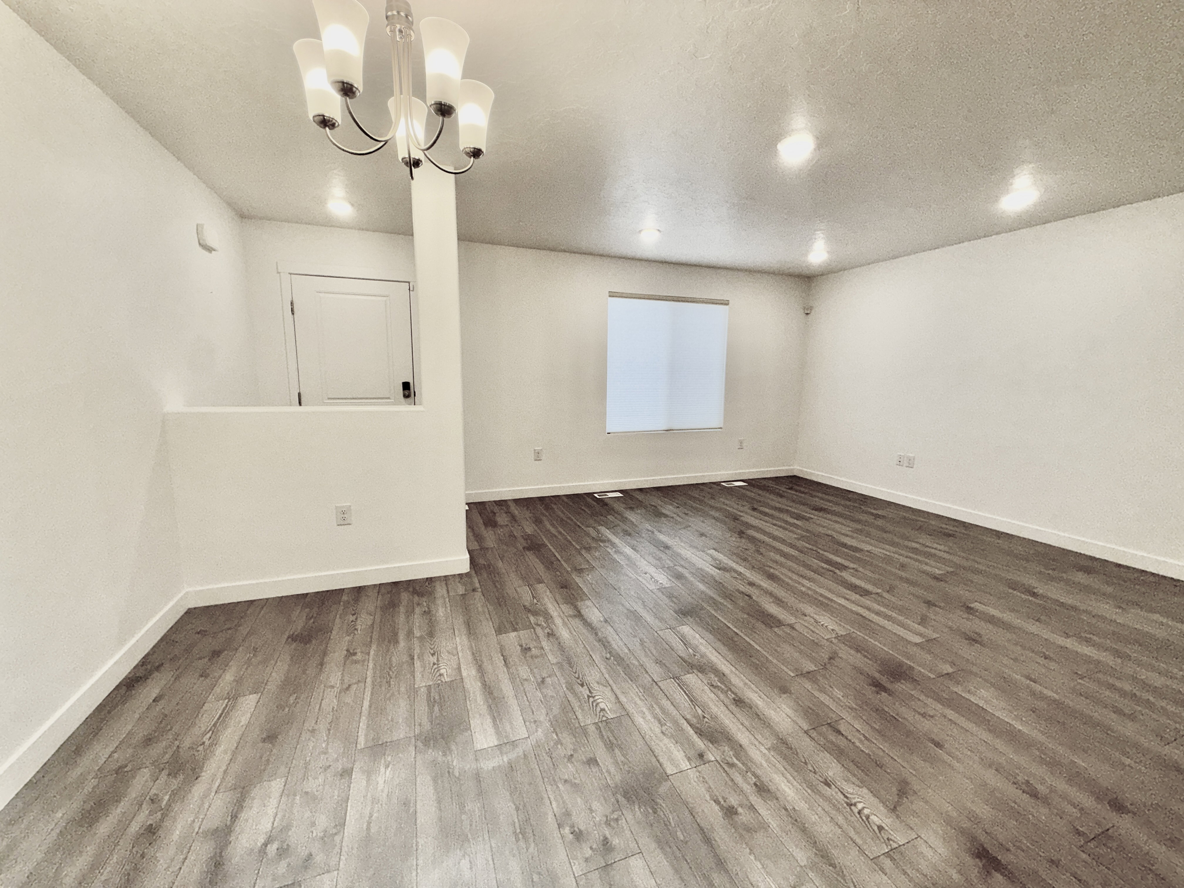 Spacious room featuring wood-finish flooring, recessed lighting, and a contemporary chandelier
