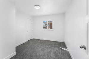 Unfurnished room featuring dark carpet and baseboards