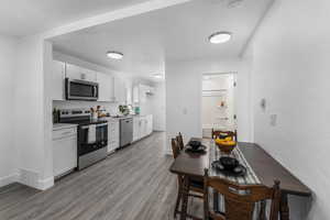 Kitchen featuring appliances with stainless steel finishes, white cabinets, visible vents, and light wood finished floors