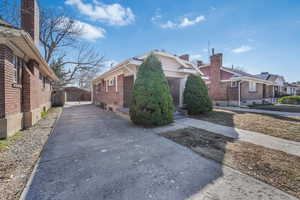 View of property exterior with a residential view, concrete driveway, and brick siding