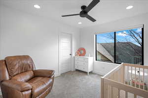 Bedroom with a nursery area, recessed lighting, a ceiling fan, and light colored carpet