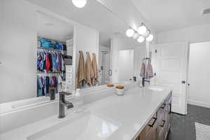 Full bathroom featuring double vanity, a stall shower, a spacious closet, and a sink