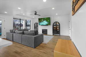 Living area with a brick fireplace, light wood-style flooring, a ceiling fan, and recessed lighting