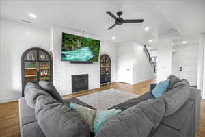 Living room featuring recessed lighting, visible vents, a fireplace, and wood finished floors