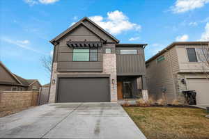 View of front of property featuring brick siding, board and batten siding, fence, a garage, and driveway