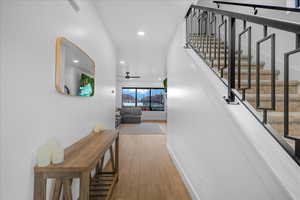 Hallway featuring stairs, baseboards, wood finished floors, and recessed lighting