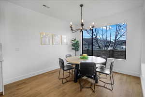 Dining room with light wood-type flooring, visible vents, a notable chandelier, and baseboards