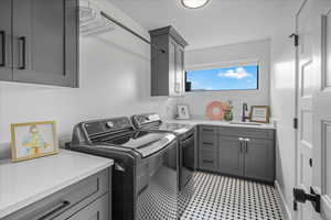 Clothes washing area featuring cabinet space, a sink, and separate washer and dryer