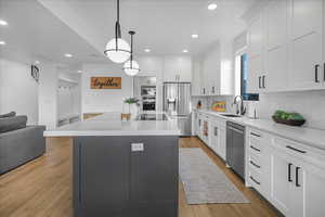 Kitchen featuring appliances with stainless steel finishes, a sink, light wood-style flooring, and white cabinets