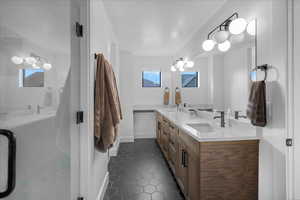 Full bathroom featuring baseboards, double vanity, a sink, and tile patterned floors