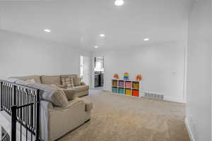 Carpeted living room with baseboards, visible vents, and recessed lighting