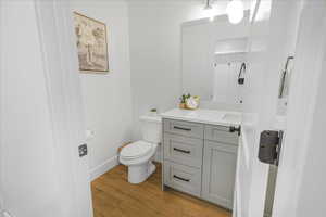 Half bath featuring vanity, wood finished floors, toilet, and baseboards