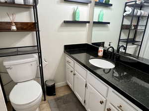 Bathroom featuring toilet, tile patterned flooring, baseboards, and vanity