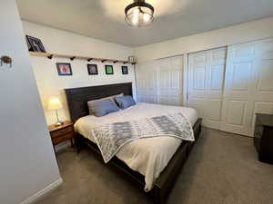 Bedroom featuring baseboards, dark carpet, and a closet