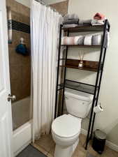 Full bath with shower / bath combo, tile patterned flooring, toilet, and baseboards