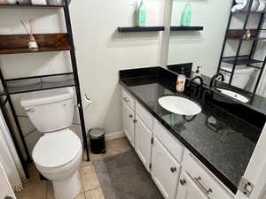 Bathroom with tile patterned flooring, baseboards, vanity, and toilet