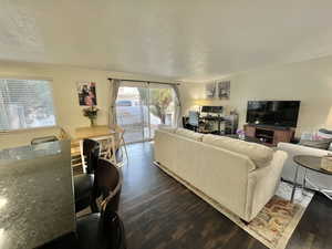 Living room with dark wood-style floors, ornamental molding, and a textured ceiling