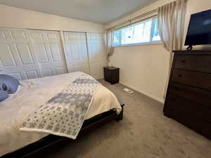 Carpeted bedroom with a closet, visible vents, vaulted ceiling, and baseboards