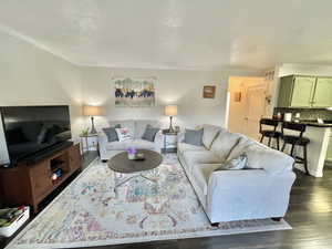 Living room featuring ornamental molding, dark wood-style flooring, and visible vents