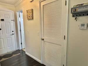 Foyer entrance featuring ornamental molding, dark wood-type flooring, and baseboards