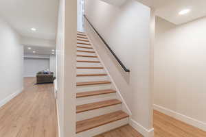 Staircase featuring baseboards, wood finished floors, and recessed lighting