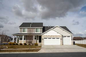 Craftsman-style house featuring board and batten siding, fence, a garage, stone siding, and driveway